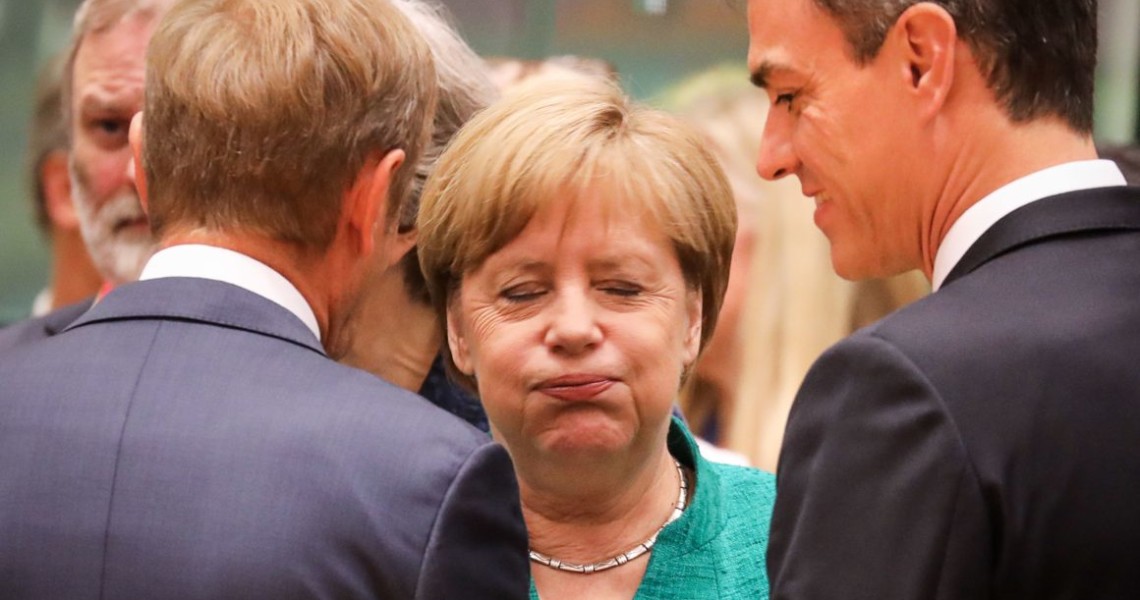 TOPSHOT - Germany's Chancellor Angela Merkel (C) reacts as she speaks with European Council President Donald Tusk (L) and Spain's Prime Minister Pedro Sanchez during an European Union leaders' summit focused on migration, Brexit and eurozone reforms on June 28, 2018 at the Europa building in Brussels. - The two-day meeting in Brussels is expected to be dominated by deep divisions over migration, with German Chancellor saying the issue could decide the fate of the bloc itself. (Photo by Ludovic MARIN / AFP)        (Photo credit should read LUDOVIC MARIN/AFP/Getty Images)
