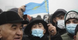 Demonstrators, one of which holds a national flag, gather near a police line during a protest in Almaty, Kazakhstan, Wednesday, Jan. 5, 2022. Demonstrators denouncing the doubling of prices for liquefied gas have clashed with police in Kazakhstan's largest city and held protests in about a dozen other cities in the country. (AP Photo/Vladimir Tretyakov)