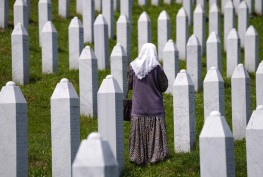 A woman walks stands among the graves of victims of the Srebrenica massacre, at the memorial cemetery in Potocari, near Srebrenica, eastern Bosnia, Tuesday, June 8, 2021. Tuesday the United Nations court in The Hague, Netherlands, delivers its verdict in the appeal by former Bosnian Serb military chief Ratko Mladic against his convictions for genocide and other crimes and his life sentence for masterminding atrocities throughout the Bosnian war. (AP Photo/Darko Bandic)
