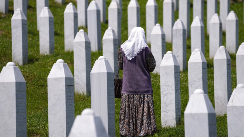A woman walks stands among the graves of victims of the Srebrenica massacre, at the memorial cemetery in Potocari, near Srebrenica, eastern Bosnia, Tuesday, June 8, 2021. Tuesday the United Nations court in The Hague, Netherlands, delivers its verdict in the appeal by former Bosnian Serb military chief Ratko Mladic against his convictions for genocide and other crimes and his life sentence for masterminding atrocities throughout the Bosnian war. (AP Photo/Darko Bandic)