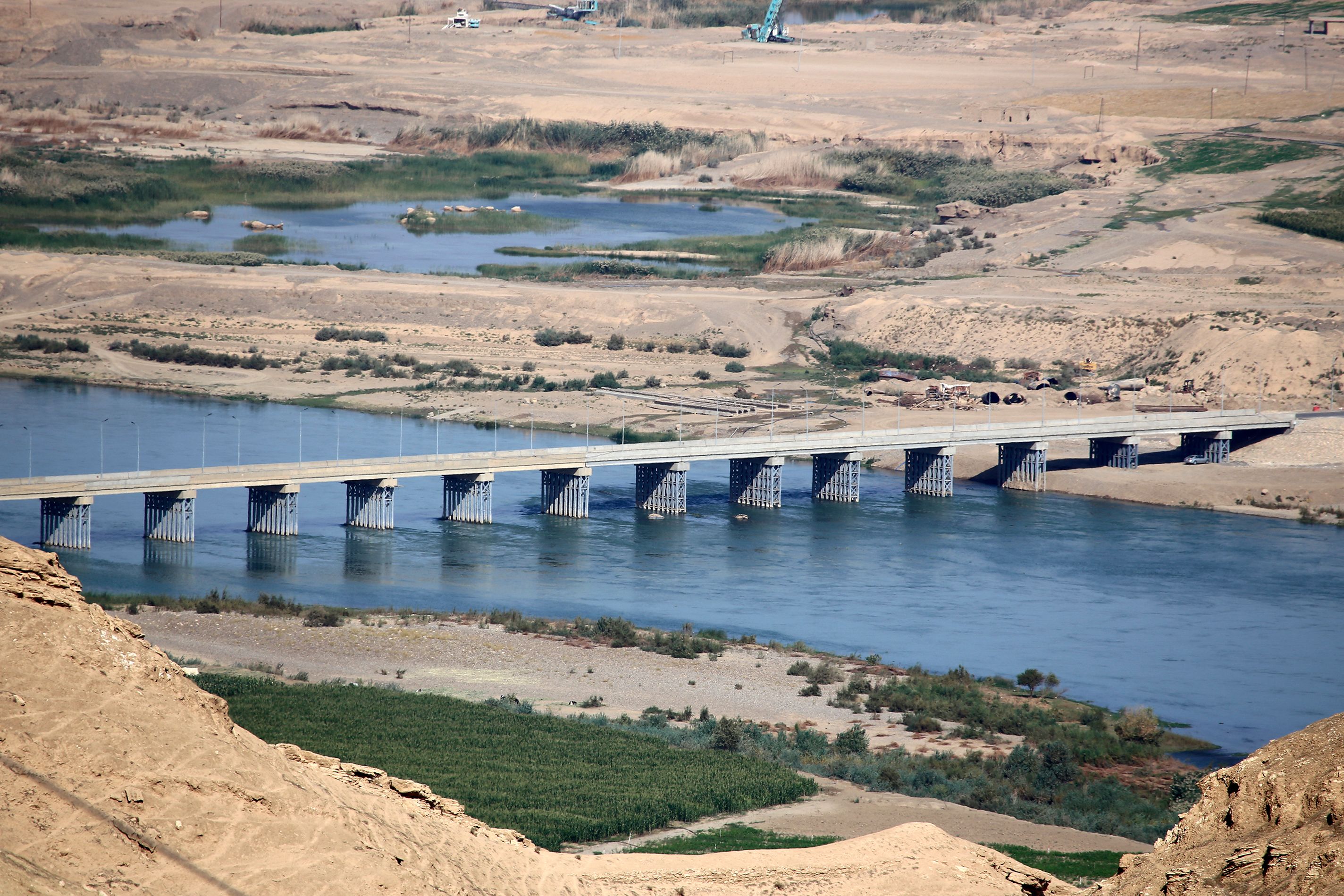 A bridge spans the Tigris river near the Makhoul dam site, in northern Iraq's Salaheddine province, on November 1, 2022. - In a country threatened by climate change, apparent in three consecutive years of drought ,authorities defend Maqhoul dam project, which will allow, among other things, water to be stockpiled against shortages. However, NGOs decry the repurcussions on around 30 villages ,home to nearly 120,000 people, and the threats to biodiversity at several archaeological sites. (Photo by Sabah ARAR / AFP)