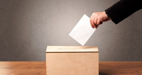 Ballot box with person casting vote on blank voting slip, grungy background